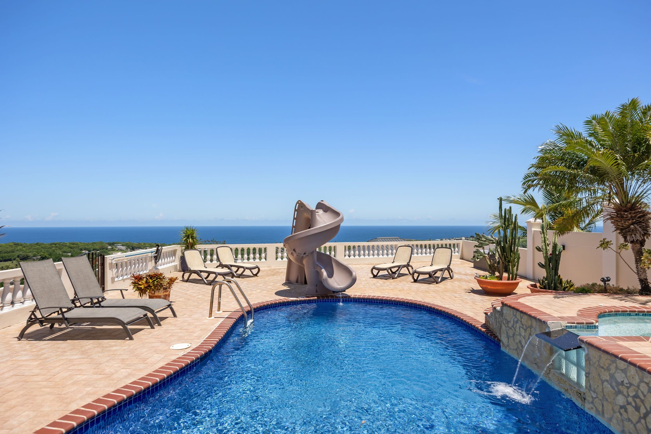 Heated pool with waterslide and ocean views